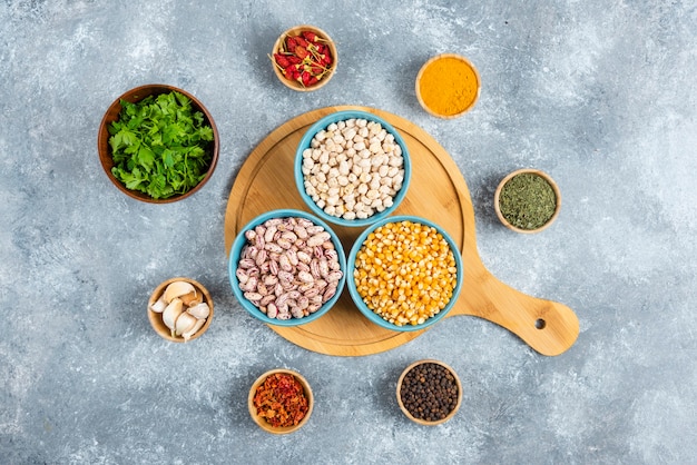 Blue bowls of raw beans on wooden board.