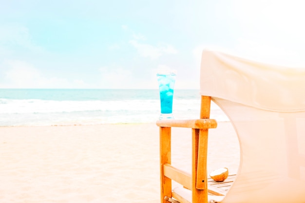 Blue bright drink on arm of wooden chair and coconut