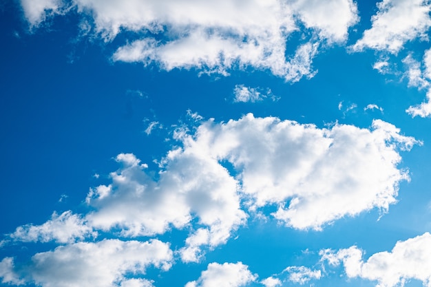 Blue bright sky with few clouds and a shining sun