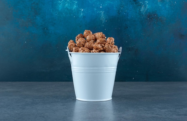 Free photo blue bucket filled with popcorn candy on blue