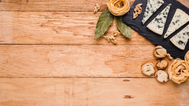 Free Photo blue cheese; bread; pasta and bay leaves on black stone over worktop with space for text