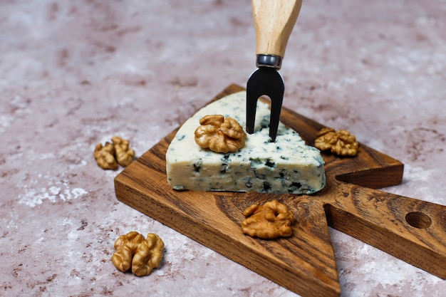 Free photo blue cheese on wooden cutting board with honey and walnuts