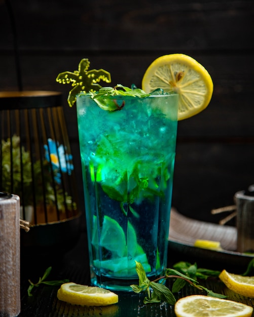 Blue cocktail with mint and lemon in a glass.