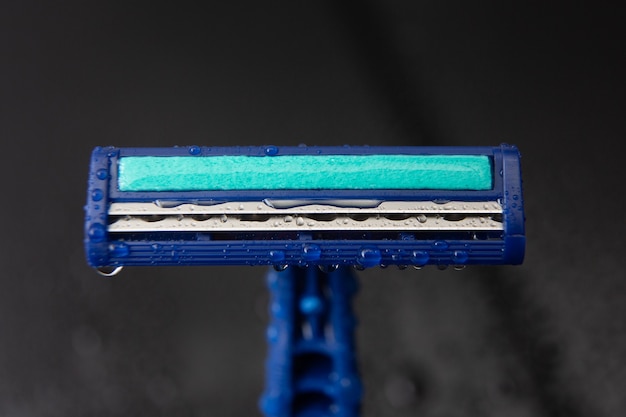 Blue disposable razor blade with water drops