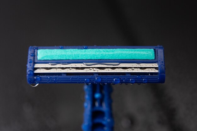 Blue disposable razor blade with water drops