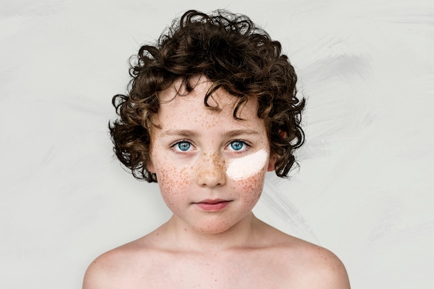 Free photo blue eyed boy with freckles and white paint on his cheek