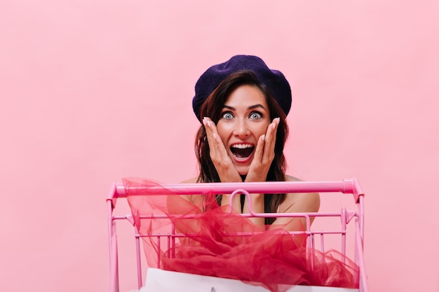 Free photo blue-eyed woman in black beret looks at camera in surprise on pink background. happy beautiful girl with dark hair posing on isolated.