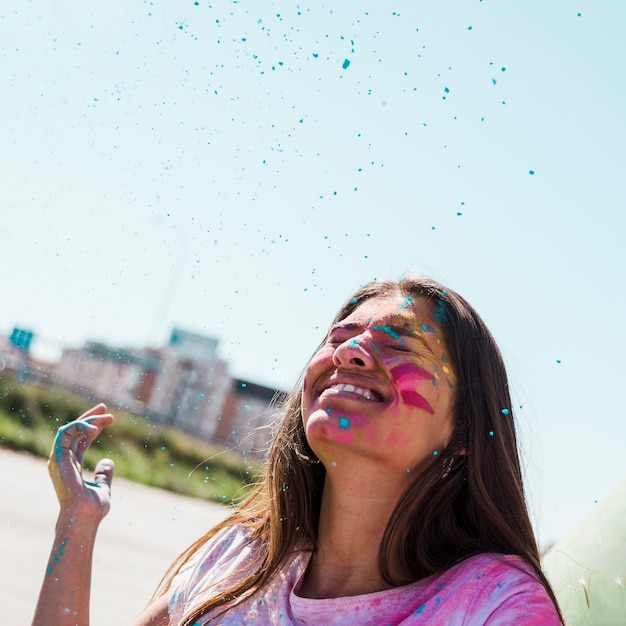 Free photo blue holi powder over the smiling young woman outdoors