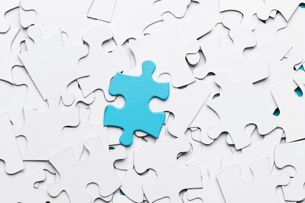 Free photo blue jigsaw puzzle piece over white puzzle pieces