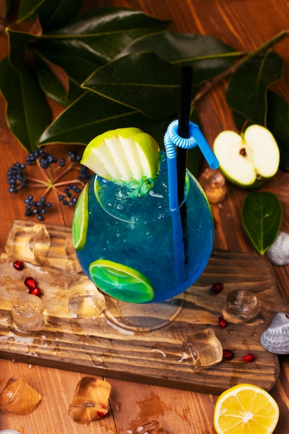 Blue lagoon cocktail with lemon slices in glass on wooden table