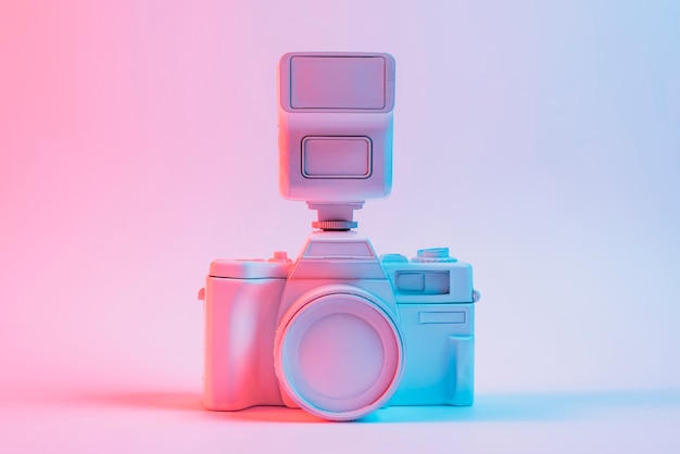 Blue light on vintage painted pink camera against pink backdrop