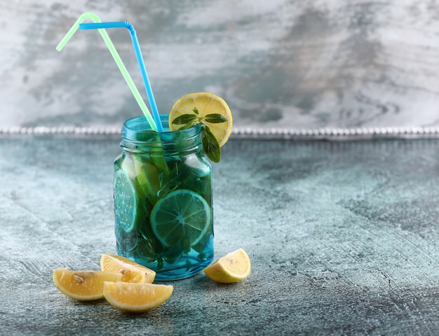 Free photo a blue mojito jar with lemon and mint on shiny background.