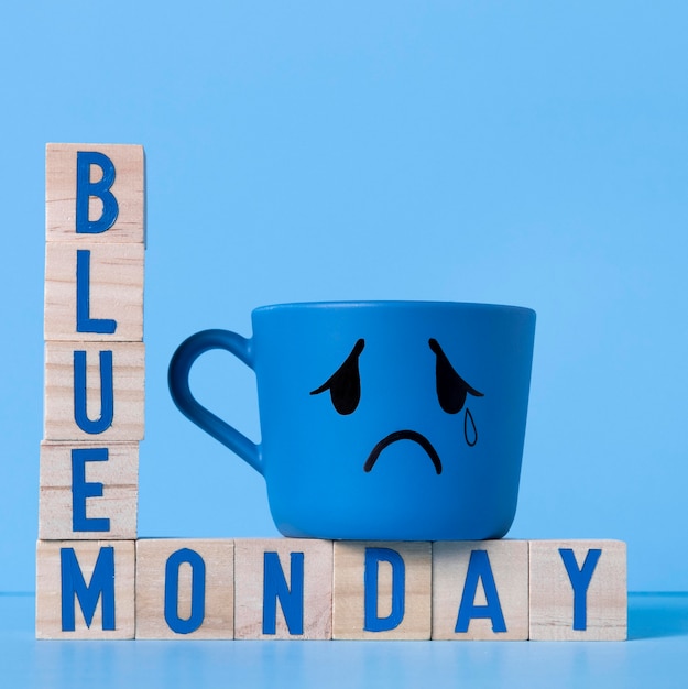 Free photo blue monday with wooden cubes and crying mug