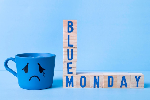 Free Photo blue monday with wooden cubes and teary mug