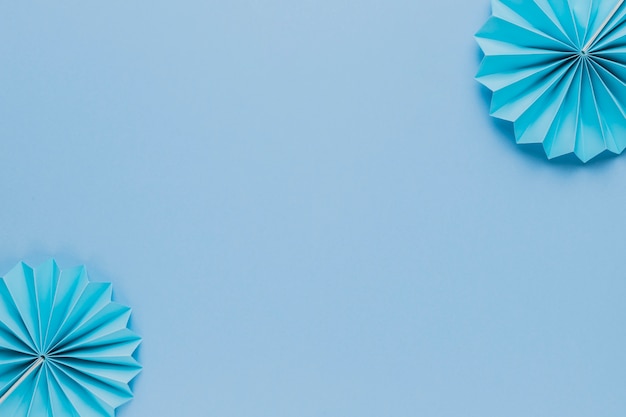 Blue origami paper fan at the corner of blue backdrop