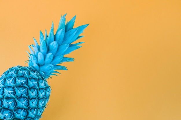 Free photo blue painted pineapple against yellow backdrop