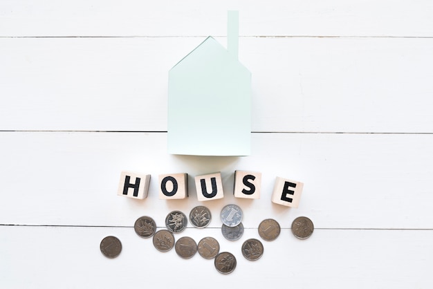 Free Photo blue paper house model with wooden blocks and coins on white wooden backdrop