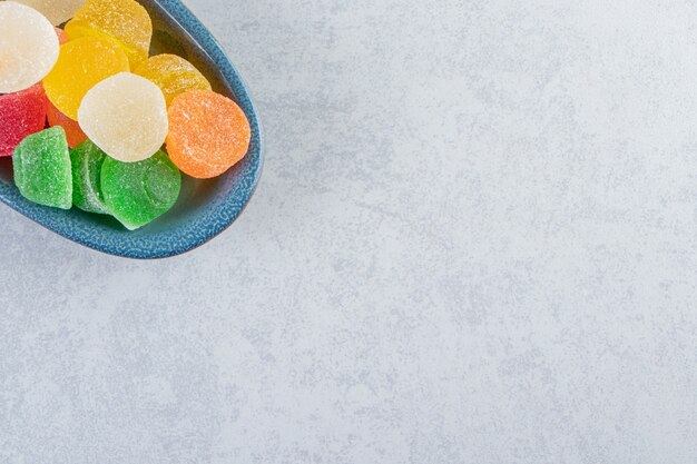 Blue plate of colorful jelly marmalades on marble background.