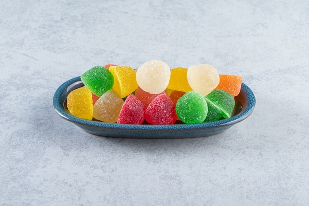 Blue plate of colorful jelly marmalades on marble.