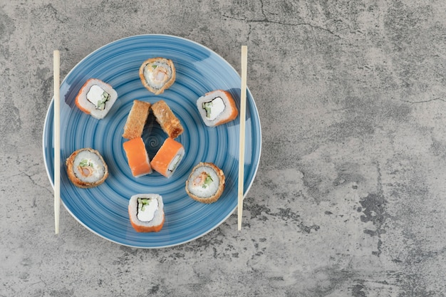 Free photo blue plate of delicious sushi rolls on marble background