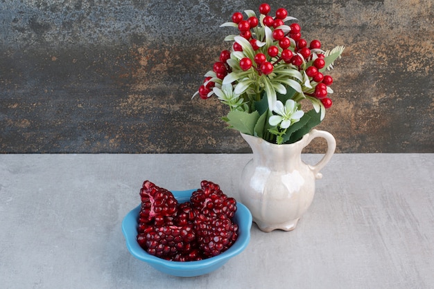 A blue plate full of pomegranate on gray table.