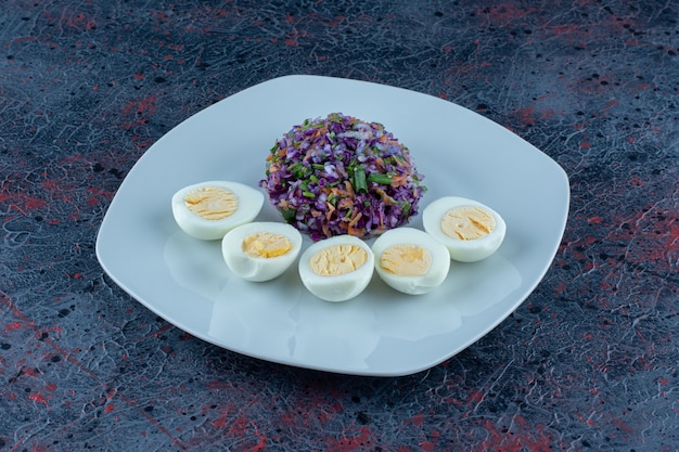 Free Photo a blue plate of hard boiled eggs with vegetables.