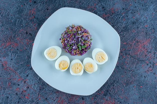 Free Photo a blue plate of hard boiled eggs with vegetables. 