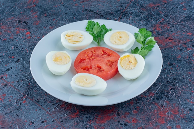 A blue plate of hard boiled eggs with vegetables. 