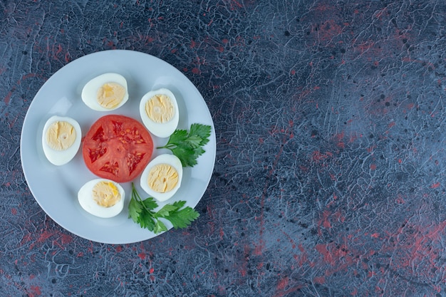 A blue plate of hard boiled eggs with vegetables