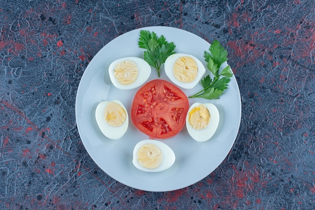 Free Photo a blue plate of hard boiled eggs with vegetables