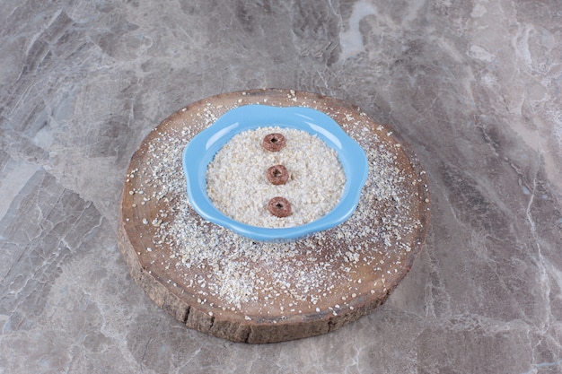 A blue plate of healthy oatmeal porridge with chocolate cereal rings . 