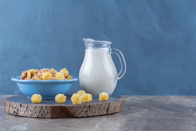 Free photo a blue plate of healthy sweet cornflakes with a glass jar of milk on a wooden piece .