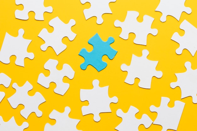 Free Photo blue puzzle with white jigsaw piece on yellow background