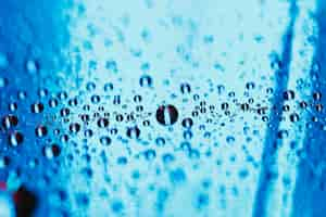 Free photo blue reflective glass with water droplets backdrop