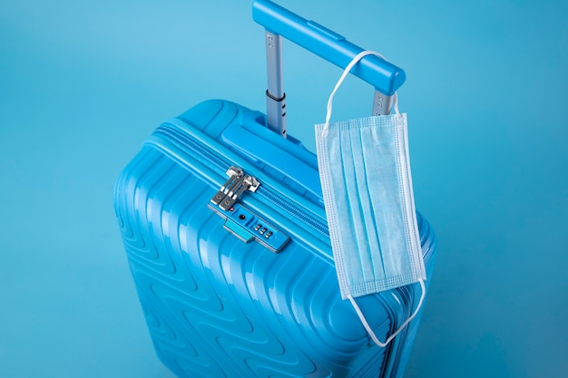 Free Photo blue suitcase for travel with medical mask