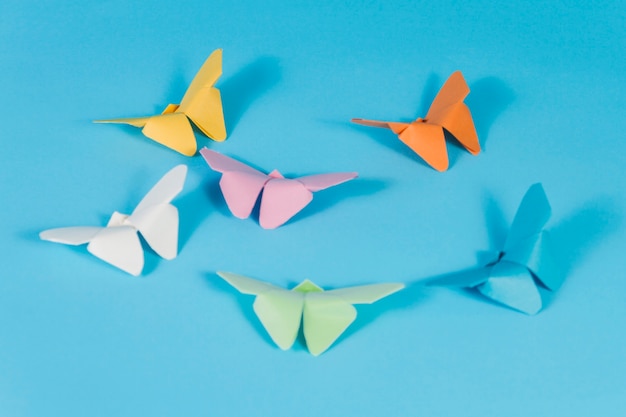 Free photo blue surface with paper butterflies