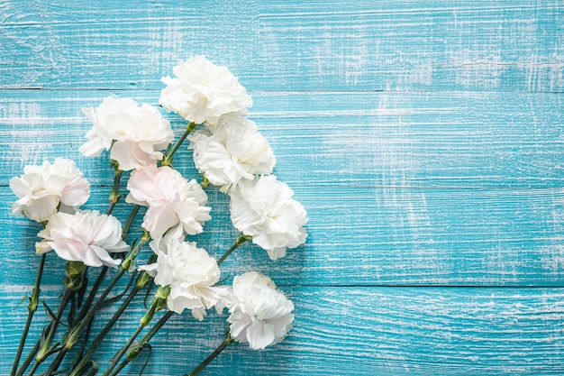 Free photo blue wooden background with white flowers flat lay