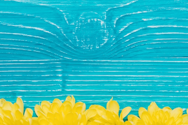 Blue wooden background with yellow petals