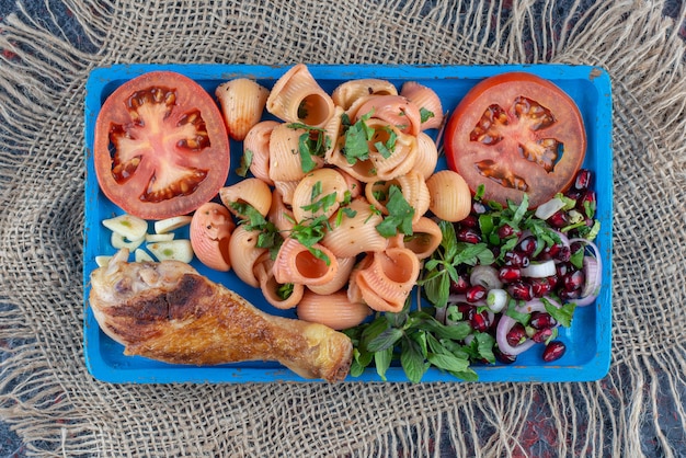 Free Photo a blue wooden board of chicken leg and macaroni