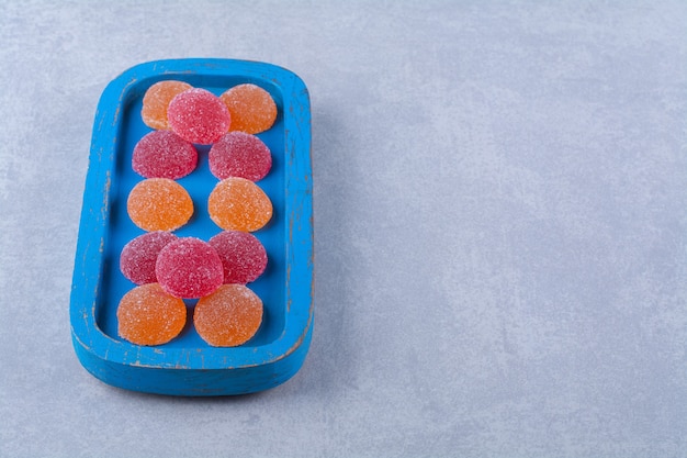 Free photo a blue wooden board full of red and orange sugary marmalades