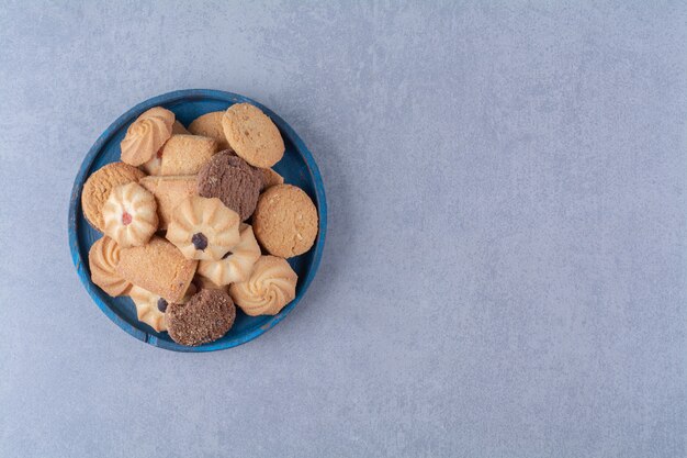 A blue wooden board with sweet round delicious cookies on sackcloth . 