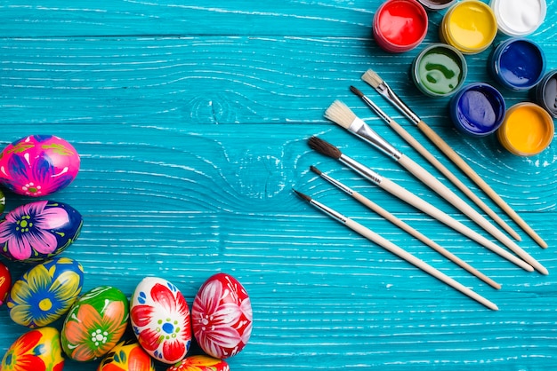 Blue wooden surface with easter eggs and paint brushes