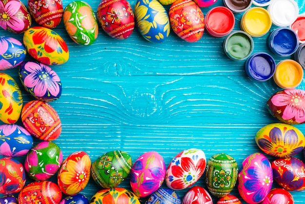 Blue wooden surface with easter eggs and paint jars