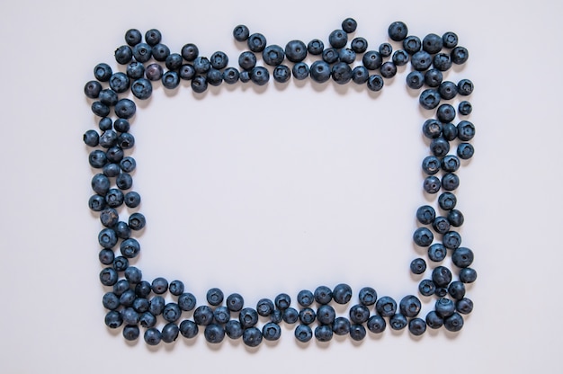 Blueberries isolated on white background. Blueberry border design. Ripe and juicy fresh picked bilberries close up. Copyspace. Top view or flat lay