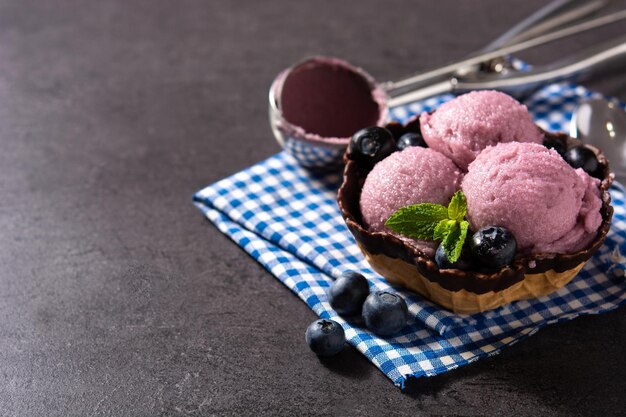 Blueberry ice cream scoop on black slate background