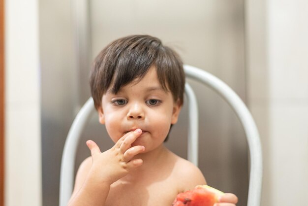 Blueeyed baby boy eating watermelon