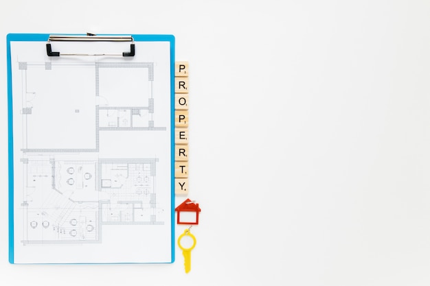 Free Photo blueprint clipboard with property blocks and house key on white backdrop