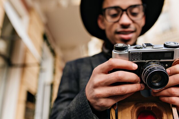 Blur portrait of concentrated african photographer isolated on city street. Outdoor photo of stylish black man with camera in focus.