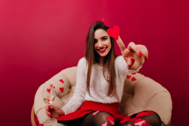 Free Photo blur portrait of long-haired girl with her hand holding heart in focus