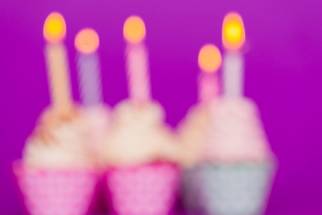 Free photo blurred birthday cupcakes with lit candles